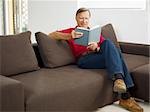senior man reading book at home and smiling