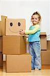 Little girl with lots of cardboard boxes grimacing in her new home - moving concept