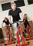Group of people having spinning class with a young man in focus