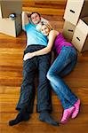 Couple lying on the floor with boxes around. Moving house