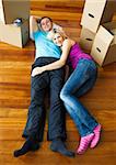 Happy couple relaxing on the floor with boxes around. Moving house