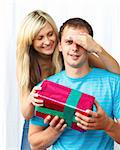 Woman giving a present to her boyfriend and covering his eyes with her hand