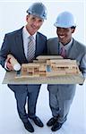 High angle of engineers with hard hats holding a model house