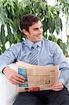 Relaxed businessman reading a newspaper and smiling
