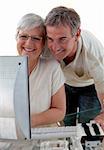 Smiling senior couple using a computer at home