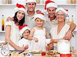 Children baking Christmas cakes in the kitchen with their parents and grandparents