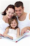 Young attractive family reading together in bed