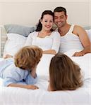 Smiling family playing in bed