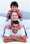 Happy parents and son playing in bed together