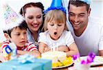 Little girl blowing out candles in her birthday with her family