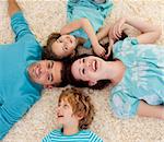 Smiling family lying on floor in a circle with heads together