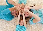 Happy family lying on floor in a circle with heads and hands together