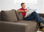 senior man reading newspaper at home and smiling