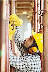 latin american construction worker fastening girder. Side view