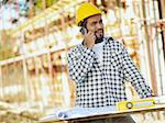 latin american construction worker talking on mobile phone. Copy space
