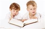 Two little boys read the book in the bed, isolated