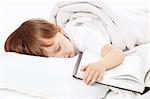 Little boy sleeps in bed embracing the book, isolated