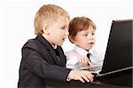 Two little boys in business suits together look in the screen of the laptop, isolated