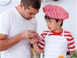 Boy hurt his finger and father treating it in kitchen
