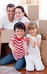 Happy family moving house with boxes around and thumbs up