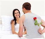 Man giving a rose to his beautiful wife in bed