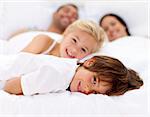 Young family resting together in parent's bed