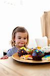 Little girl looking at colorful confectionery at home