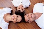 High angle of parents and kid lying on floor with heads together