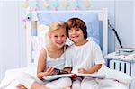 Smiling children reading a book in bedroom