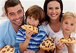 Portrait of happy family eating pizza in living-room all together