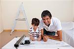 Happy father and son making architectural works in bedroom