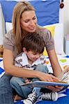 Mother reading a book with her son in bedroom