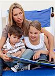 Mother reading a book with her children in bedroom