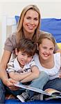 Portrait of mother reading a book with her children in bedroom