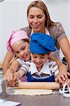 Smiling mother and children baking cookies in the kitchen