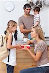 Mother giving her daughter the school lunch in the kitchen