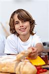 Smiling child eating bread in the kitchen