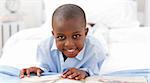 Small boy reading a book on his bed