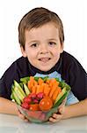Healthy boy holding a bowl full of fresh vegetables - isolated