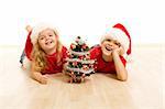 Happy kids on the floor at christmas time with a small decorated tree - isolated