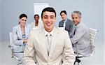 Young businessman smiling in a meeting with his colleagues working in the background