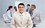 Confident businessman smiling in a meeting with his team working in the background