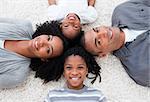 Smiling Afro-American young family lying on floor in a circle