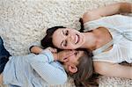 Little girl telling a secret to her mother lying on the floor