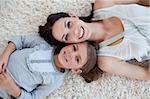 Happy mother and her girl lying on the floor with heads together