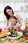 Little girl cooking with her mother in the kitchen