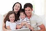 Smiling young family using a laptop in the living-room