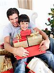 Happy father and son holding Christmas presents at home