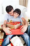 Father kissing his son after giving him a Christmas gift in the living-room