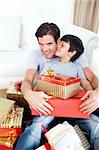 Son kissing his father after receiving a Christmas gift in the living-room